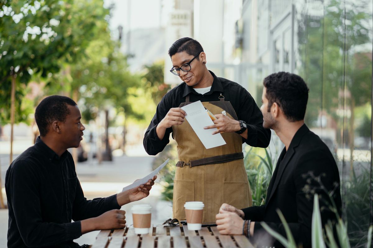 Barista taking orders at outdoor cafe seating